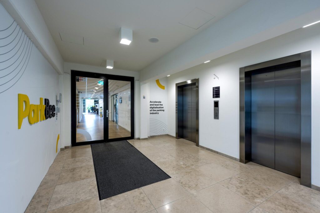 Modern elevator lobby at ParkBee office on Mr. Treublaan with two elevators and glass doors leading to the workspace.